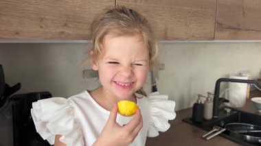 Mutfakta otururken limon tadı alan küçük bir kız. Yüksek kalite 4k görüntü