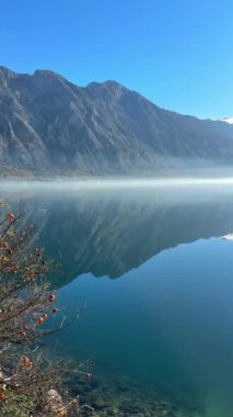 Karadağ 'ın Kotor Körfezi' nde kış sabahı bir sis şeridiyle ayrılan bulutlu dağlar ve deniz sularındaki yansımaları. Yüksek kalite 4k görüntü