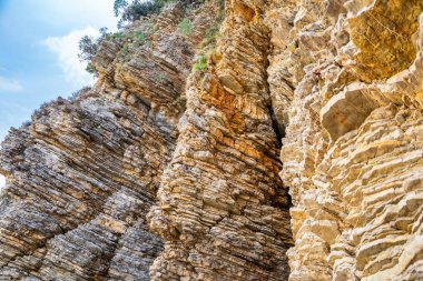 Karadağ 'ın Budva kentindeki katmanlı kaya dokusu. Gri ve kahverengi engebeli tortulu kayalar. Katmanların ve çatlakların doğal oluşumu, jeolojik yapı. Yüksek kalite fotoğraf