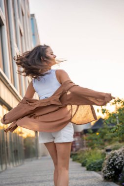 Çekici genç bir kadın gün batımında boş zamanlarının tadını çıkarıyor. Yazın mutlu kız portresi. Özgürlük yaşam tarzı yaz konsepti. Arka planda güneş parlıyor. Yüksek kalite fotoğraf