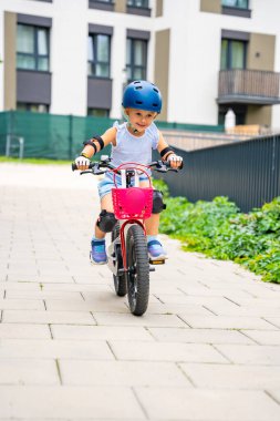 Küçük kız yazın Avrupa 'daki apartmanların avlusunda iki tekerlekli bisiklet sürüyor. Yüksek kalite fotoğraf