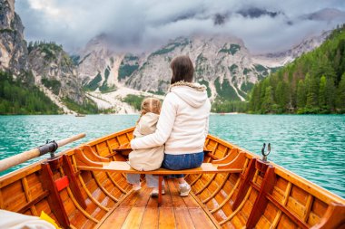 İtalya 'nın bulutlu bir gününde kızıyla birlikte Lago di Braies gölünde büyük kahverengi bir teknede oturan bir kadın. Avrupa 'da aile tatili. Yüksek kalite fotoğraf