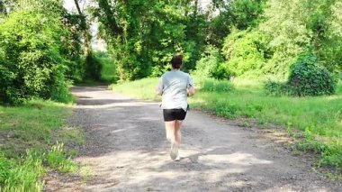 Yaz parkında genç bayan koşucu eğitimi. Spor salonundaki kadın dışarıda koşuyor. Sabah koşusu kavramı. Yüksek kalite 4k görüntü