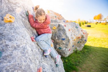 Oyun parkında yapay bir tırmanma duvarına tırmanan küçük bir kız güç ve koordinasyon geliştiriyor. Yüksek kalite fotoğraf