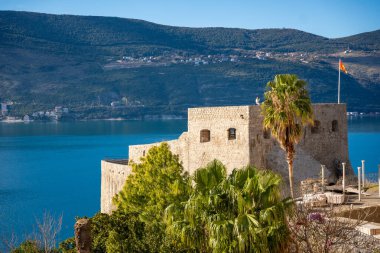 Herceg Novi 'deki Adriyatik Denizi' ne bakan Karadağ bayrağına sahip antik bir kale. Taş duvarlar, bereketli palmiye ağaçları ve mavi sularla tezat oluşturarak pitoresk bir manzara yaratıyor. Yüksek kalite fotoğraf