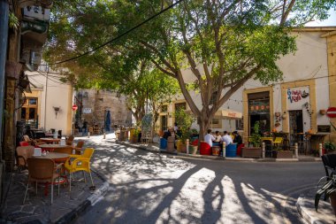 Girne, Kuzey Kıbrıs - 3 Şubat 2025: Kyrenia şehir merkezinde yayalar, kafeler, dükkanlar ve yürüyen turistlerle dolu bir sokak, Kuzey Kıbrıs. Yüksek kalite fotoğraf