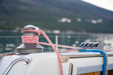 Kotor Körfezi 'nin manzaralı arka planına karşı kırmızı ve mavi halatları olan bir yat vincinin yakın çekimi. Yelkencilik, deniz macerası ve deniz hayatı anlayışı. Yüksek kalite fotoğraf