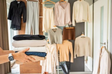 Giysi yığını yeniden satışa, bağışa ya da geri dönüşüme hazır kadın ellerinde. Sürdürülebilir moda seçimleri ikinci el kullanımı destekler, atıkları azaltır ve bilinçli tüketimi teşvik eder. Yüksek kalite fotoğraf