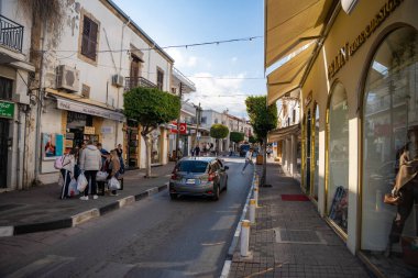 Girne, Kuzey Kıbrıs - 3 Şubat 2025: Kyrenia şehir merkezinde yayalar, arabalar, kafeler, dükkanlar ve yürüyen turistlerle dolu bir sokak, Kuzey Kıbrıs. Yüksek kalite fotoğraf