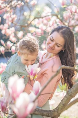 Prag parkındaki manolya ağaçlarının altında küçük kızıyla modaya uyan bir anne. Modern bir ebeveynlik yaklaşımıyla şık bir aile anı yakalamak. Yüksek kalite fotoğraf