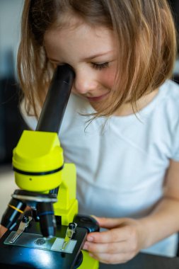 Küçük kız yeşil bir mikroskoptan bakıyor. Merakın ve erken bilimsel keşiflerin kavramı. Yüksek kalite fotoğraf