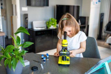 Küçük kız yeşil bir mikroskoptan bakıyor. Merakın ve erken bilimsel keşiflerin kavramı. Yüksek kalite fotoğraf