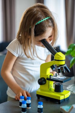Küçük kız yeşil bir mikroskoptan bakıyor. Merakın ve erken bilimsel keşiflerin kavramı. Yüksek kalite fotoğraf
