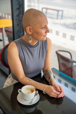 Kanserli, kendine güvenen, kafede kahve içen, hastalığa rağmen hayatı kucaklayan genç bir kadın. Konsept gösteriyor ki kanser teşhisi normal aktivitelerden zevk alma yeteneğini ortadan kaldırmıyor.. 