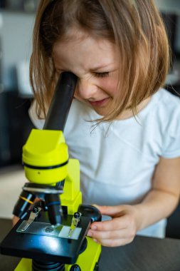 Küçük kız yeşil bir mikroskoptan bakıyor. Merakın ve erken bilimsel keşiflerin kavramı. Yüksek kalite fotoğraf