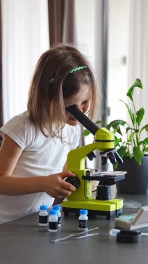 Küçük kız yeşil bir mikroskoptan bakıyor. Merakın ve erken bilimsel keşiflerin kavramı. Yüksek kalite 4k görüntü