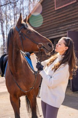 Ahırda atın yanında duran genç bir kadın. İnsanlar ve hayvanlar arasındaki duygusal bağ kavramı. Yüksek kalite fotoğraf