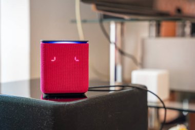 Moskova, Rusya - 21 Nisan 2025: Pembe Yandex Alice akıllı hoparlör arka planda bulanık diğer ev aletleri ile bir masada duruyor. Ses asistanı teknolojisi ve modern akıllı yaşam kavramı. 