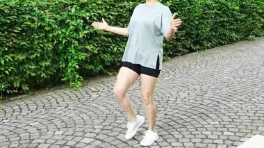 Spor giyimli genç bir kadın şehir caddesinde egzersiz yapıyor. Koşmadan ya da koşmadan önce ısın. Açık hava sporları eğitimi konsepti. Yüksek kalite 4k görüntü