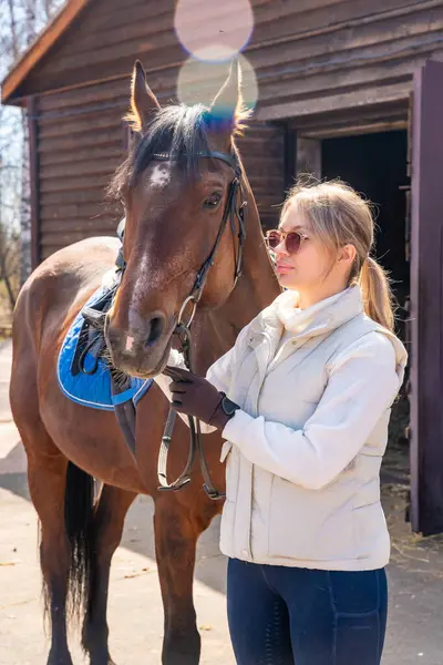 Çiftlikte atıyla poz veren genç bir kadın. Doğayla uyum içinde kadınlık ve güç kavramı. Yüksek kalite fotoğraf