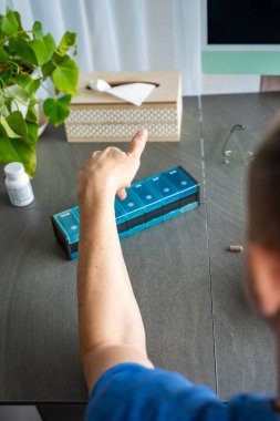 Haplarını ve takviyelerini haftalık ilaç organizatörüne ayıran bir adam. İlaç yönetimi ve günlük sağlık rutini kavramı. Yüksek kalite fotoğraf