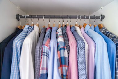 Gardıroptaki ahşap askılara asılmış erkek gömlekleri. Minimalist giyim organizasyonu ve klasik erkek moda konsepti. Yüksek kalite fotoğraf