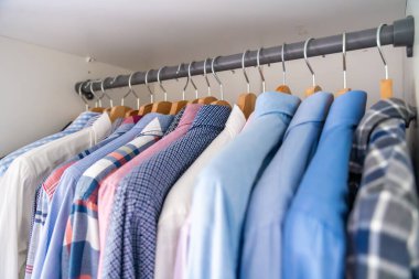 Gardıroptaki ahşap askılara asılmış erkek gömlekleri. Minimalist giyim organizasyonu ve klasik erkek moda konsepti. Yüksek kalite fotoğraf