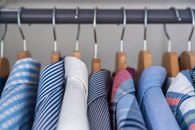 Gardıroptaki ahşap askılara asılmış erkek gömlekleri. Minimalist giyim organizasyonu ve klasik erkek moda konsepti. Yüksek kalite fotoğraf