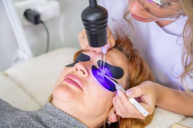 Modern güzellik salonunda ultraviyole lamba kullanarak kirpik uzatma prosedürünü kapat. Kusursuz uygulama teknikli yenilikçi kırbaç geliştirme teknolojisi. Yüksek kalite fotoğraf