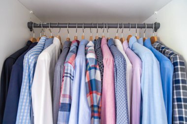 Gardıroptaki ahşap askılara asılmış erkek gömlekleri. Minimalist giyim organizasyonu ve klasik erkek moda konsepti. Yüksek kalite fotoğraf