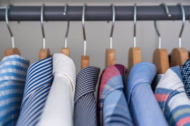 Gardıroptaki ahşap askılara asılmış erkek gömlekleri. Minimalist giyim organizasyonu ve klasik erkek moda konsepti. Yüksek kalite fotoğraf