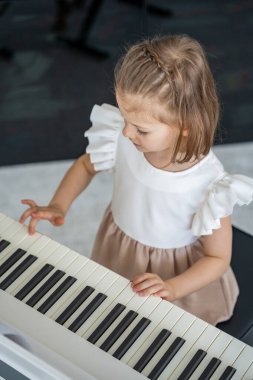 Evde, oturma odasında piyano çalan küçük bir kız. Çocukluk yaratıcılığı ve konforlu aile ortamında müzik gelişimi. Yüksek kalite fotoğraf
