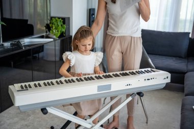 Oturma odasındaki küçük bir çocuk için özel piyano dersi. Kişisel müzik eğitimi yoluyla erken çocukluk gelişimi kavramı. Yüksek kalite fotoğraf