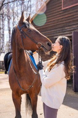 Ahırda atın yanında duran genç bir kadın. İnsanlar ve hayvanlar arasındaki duygusal bağ kavramı. Yüksek kalite fotoğraf