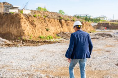 Denetmen kazı alanında sondaj noktalarını belirlemek için dolaşıyor. İnşaat projesinde toprak örnekleme ve yığın yerleştirme planları için saha değerlendirmesi. Yüksek kalite fotoğraf