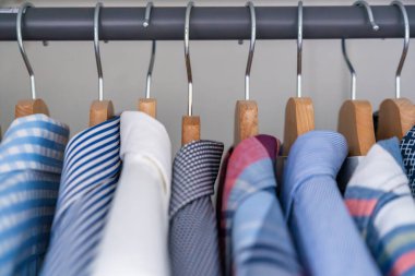 Gardıroptaki ahşap askılara asılmış erkek gömlekleri. Minimalist giyim organizasyonu ve klasik erkek moda konsepti. Yüksek kalite fotoğraf