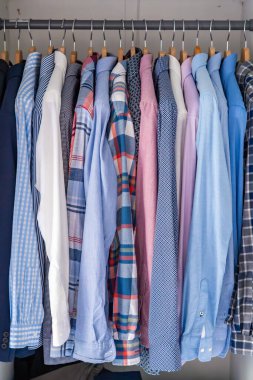 Gardıroptaki ahşap askılara asılmış erkek gömlekleri. Minimalist giyim organizasyonu ve klasik erkek moda konsepti. Yüksek kalite fotoğraf