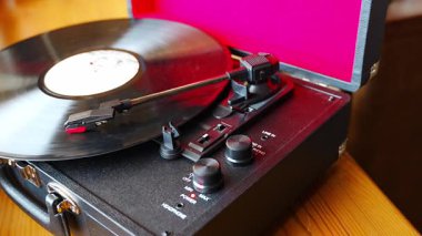 Klasik bavul tarzı plak çalar vinil plak çeviriyor. Retro müzik hareket halinde. İç mekanda nostaljik bir atmosfer yaratıyor. Yüksek kalite 4k görüntü
