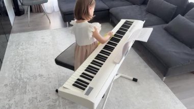 Küçük kız evde piyanosunu dikkatlice temizliyor. Müzik yoluyla erken çocukluk eğitimi enstrümana özen, sorumluluk ve saygı içerir. Yüksek kalite 4k görüntü