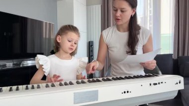 Oturma odasındaki küçük bir çocuk için özel piyano dersi. Kişisel müzik eğitimi yoluyla erken çocukluk gelişimi kavramı. Yüksek kalite fotoğraf