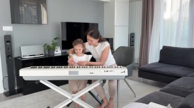 Oturma odasındaki küçük bir çocuk için özel piyano dersi. Kişisel müzik eğitimi yoluyla erken çocukluk gelişimi kavramı. Yüksek kalite fotoğraf