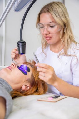 Modern güzellik salonunda ultraviyole lamba kullanarak kirpik uzatma işlemi. Kusursuz uygulama teknikli yenilikçi kırbaç geliştirme teknolojisi. Yüksek kalite fotoğraf