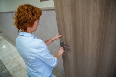 Kadın, iş gününün başında ofisinin kapısını açıyor. Giriş, yeni bir başlangıç ve günlük mesleki rutin. Yüksek kalite fotoğraf