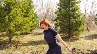 Sabah egzersizi sırasında parkta esneme hareketleri yapan bir kadın. Sağlıklı rutin, vücut hareketliliği ve aktif yaşam tarzı. Yüksek kalite 4k görüntü