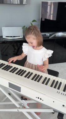 Evde müzik dersi sırasında piyano çalmayı reddeden küçük bir kız. Erken çocukluk öğrenme sürecinde oyuncu direniş ve duygusal ifade. Yüksek kalite 4k görüntü