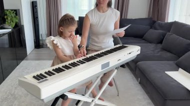 Oturma odasındaki küçük bir çocuk için özel piyano dersi. Kişisel müzik eğitimi yoluyla erken çocukluk gelişimi kavramı. Yüksek kalite fotoğraf