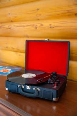 Klasik bavul tarzı plak çalar vinil plak çeviriyor. Retro müzik hareket halinde. İç mekanda nostaljik bir atmosfer yaratıyor. Yüksek kalite fotoğraf