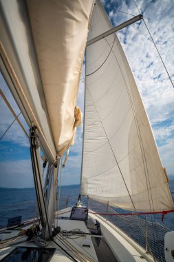 Hırvatistan yakınlarında yelken açarken rüzgar tarafından mavi gökyüzüne doğru esen tam beyaz yelkenler. Hareket, özgürlük ve yaz deniz yolculuğunun sembolü. Yüksek kalite fotoğraf