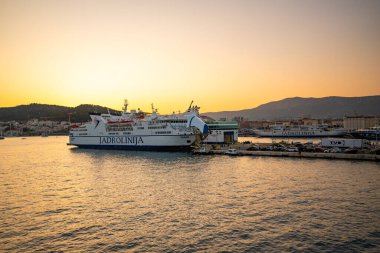 Split, Hırvatistan - 14 Haziran 2025: Jadrolinija feribotu Split rıhtımından Hırvatistan 'a ılık gün batımı ışığında hareket ediyor. Hırvatistan 'da yaz seyahati, ada ulaşımı ve deniz tatili. 
