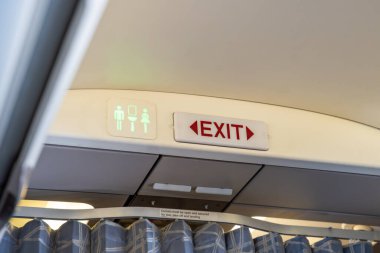 Uçağın iç kısmı çıkış ve tuvalet simgelerini gösteriyor. Uçuş güvenliği, yön tarifi ve uçak yolculuğu sırasında yolcu bilgileri. Yüksek kalite fotoğraf